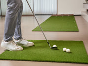 Golfer preparing to chip with a wedge on Chiputt’s complimentary chipping mat in a living room, demonstrating indoor golf practice with soft foam balls.