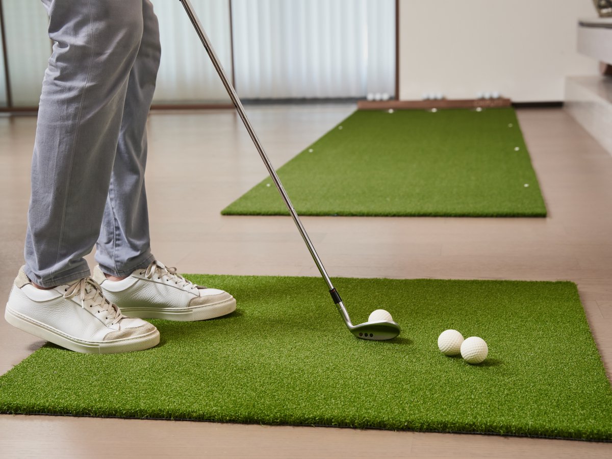 Golfer preparing to chip with a wedge on Chiputt’s complimentary chipping mat in a living room, demonstrating indoor golf practice with soft foam balls.