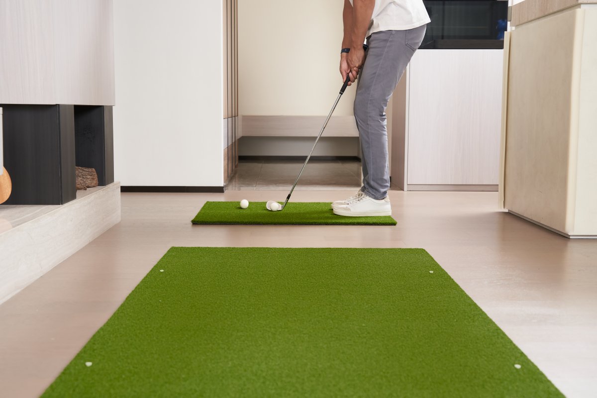 Golfer practicing a chip shot with a soft foam ball on Chiputt’s complimentary step-on mat in a modern living room, showcasing indoor golf training versatility.