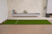 Chiputt 3 ft × 11 ft putting mat with the 2.5 ft long Dual-Hole Chipping Mat connecting to the back — total putting distance 13.5 ft, 5-hole system (3 holes on the putting mat, 2 holes at the back on the chipping mat) enabling games like HORSE and extended putting drills, modern living room setting