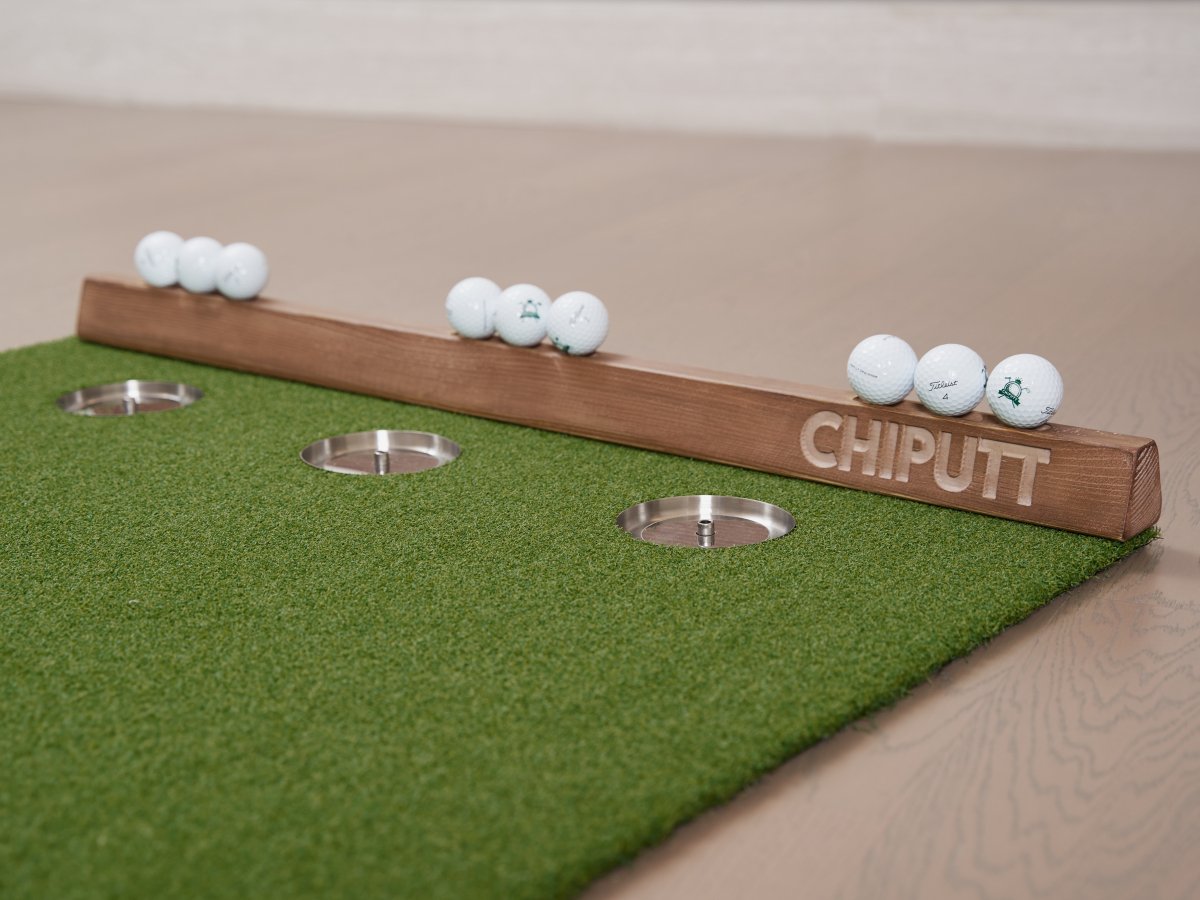 Chiputt mat displayed with Titleist Pro V1 golf balls and wooden backstop, showcasing the brand’s commitment to providing a realistic putting and chipping experience at home.