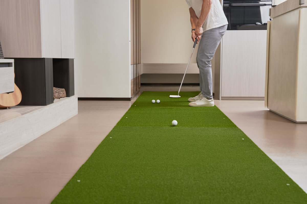 Indoor golf practice on an extended Chiputt mat, showing a golfer using the Chiputt main mat connected to a Chiputt Extender, enhancing practice distance in a modern living room setup.