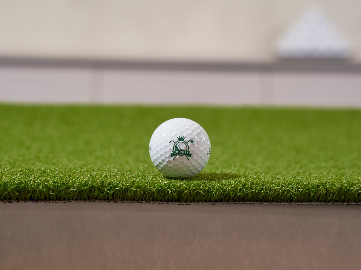 Close-up view of a Chiputt branded golf ball on a premium artificial turf putting mat, showcasing the high-quality surface and precision practice setup.