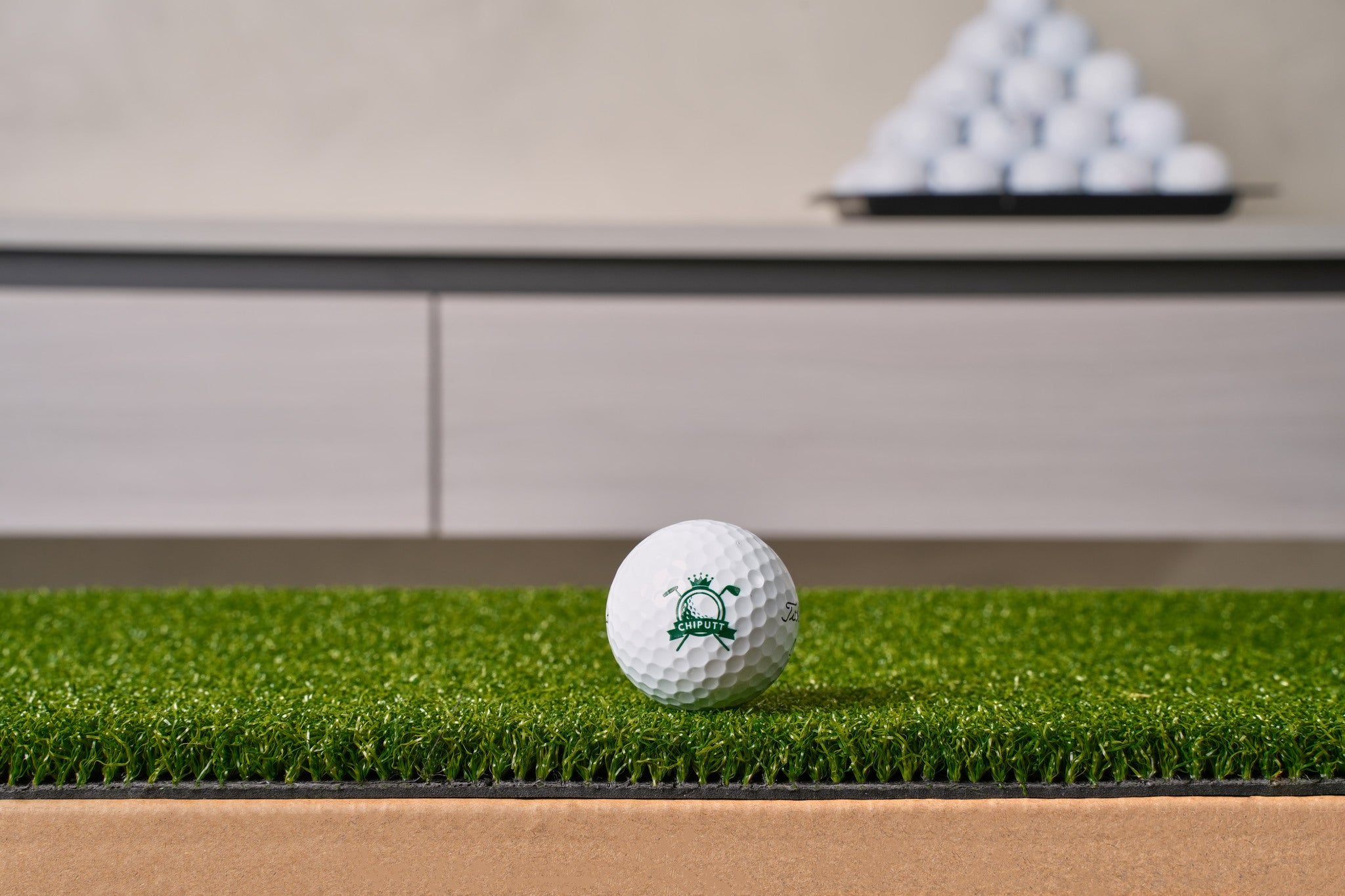 Close-up of the Chiputt tour-grade putting mat surface — dense low-pile putting turf on a heavy non-slip backing, with a Chiputt-branded golf ball resting on the mat