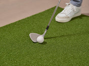 Golfer practicing chipping on Chiputt mat with a golf wedge club, demonstrating the mat’s versatile chipping capability indoors.