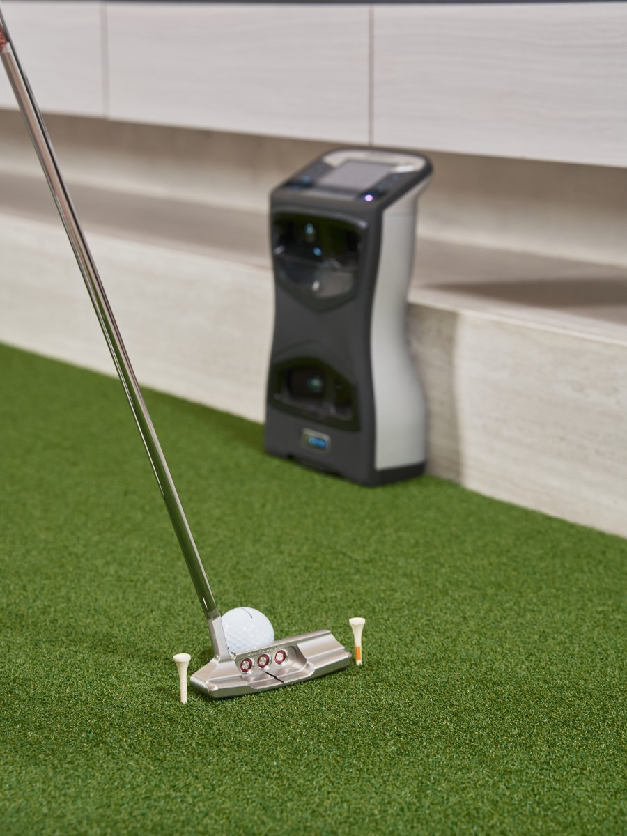 Golfer using a Scotty Cameron putter for a tee gate drill on the Chiputt mat with a Foresight GCQuad launch monitor in the background, showcasing compatibility and enhanced training with tech for accurate golf statistics.