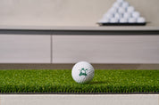 Close-up of the Chiputt tour-grade putting mat surface - dense low-pile putting turf on a heavy non-slip backing, with a Chiputt-branded golf ball resting on the mat