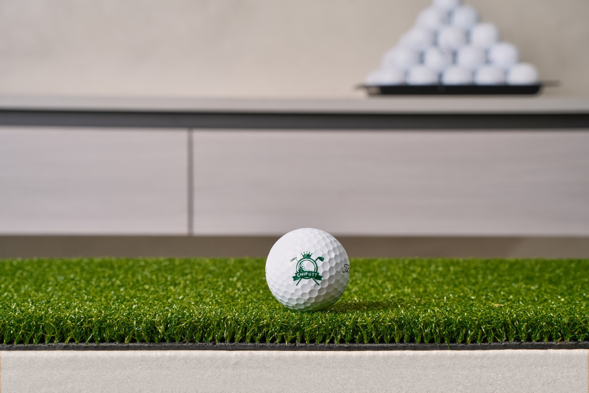 Close-up of the Chiputt tour-grade putting mat surface - dense low-pile putting turf on a heavy non-slip backing, with a Chiputt-branded golf ball resting on the mat