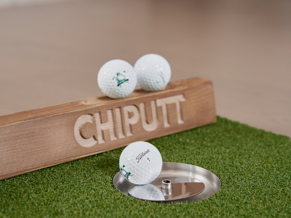 Golf ball in the cup on a Chiputt mat, highlighting the brand and providing a realistic putting experience.