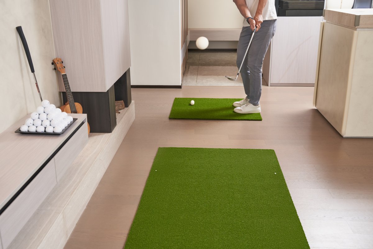 Golfer practicing chip shot on Chiputt’s complimentary step-on mat in living room, using a soft foam golf ball chipped in mid-air.