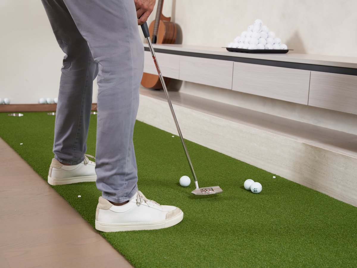 Golfer practicing a putt using a Scotty Cameron putter on a Chiputt mat, showcasing the true-roll capability of the premium turf for realistic indoor golf training.